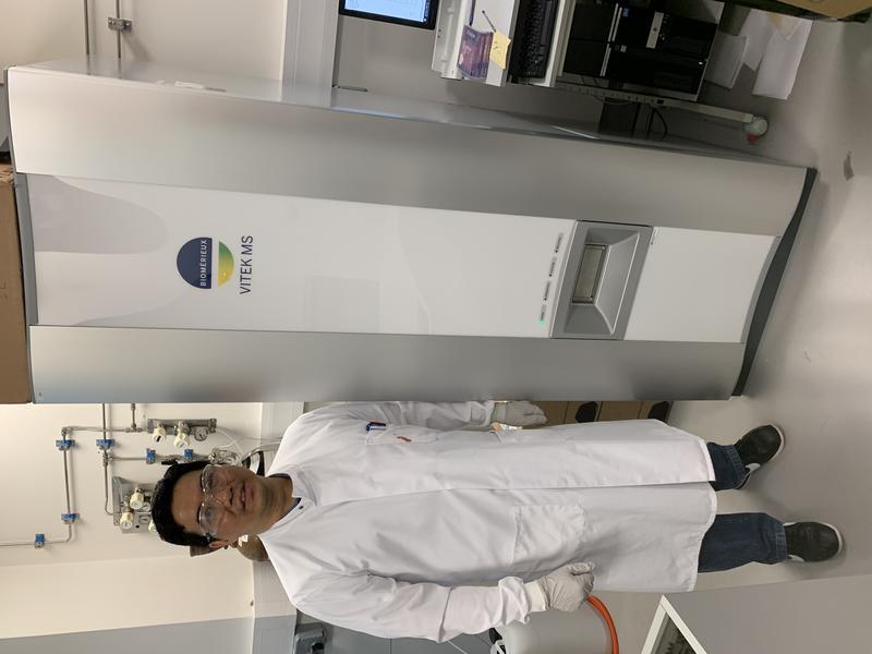 Lead author and DPhil student Yohan Arman next to the Biomerieux Vitek MS used in this study